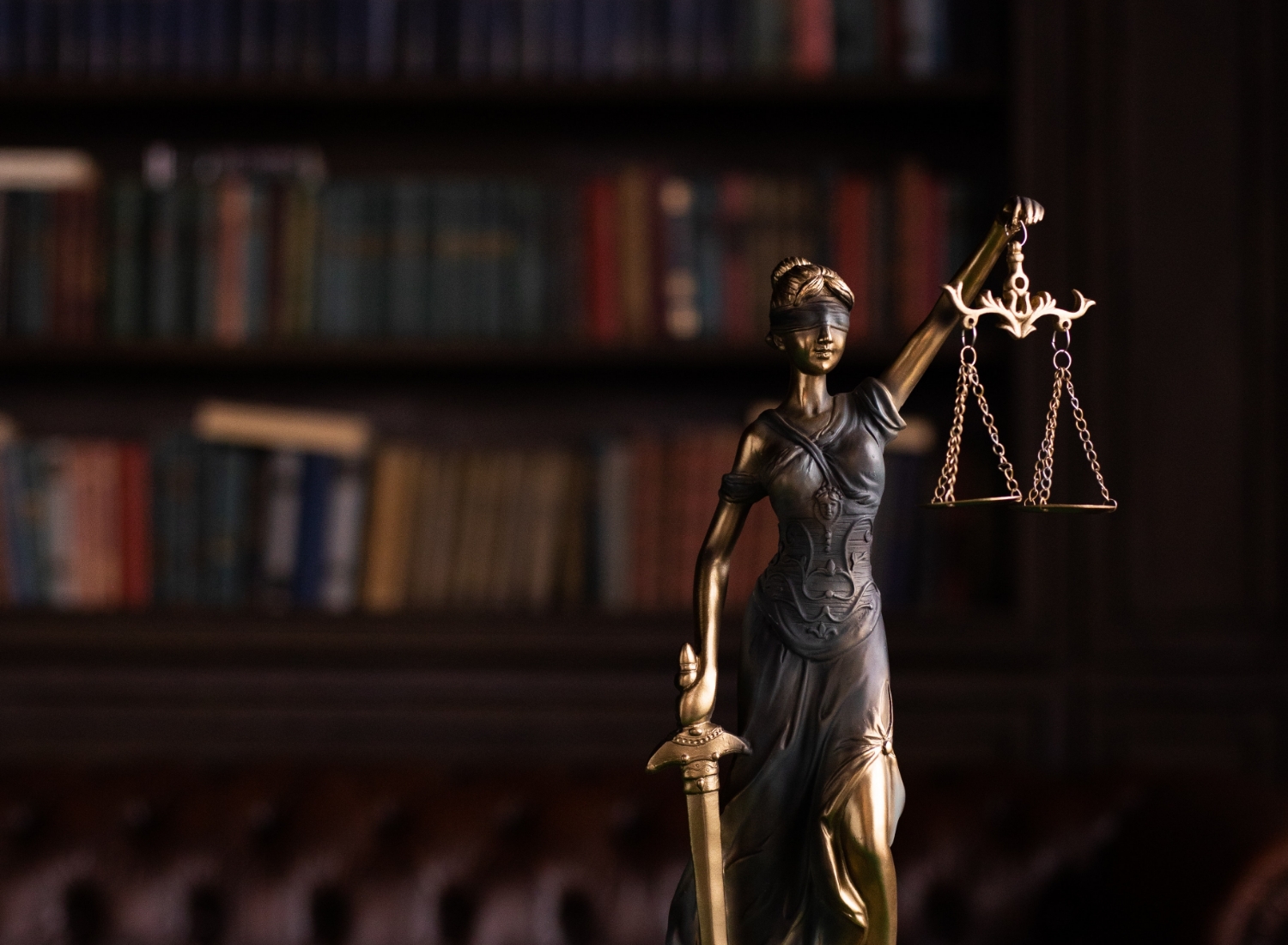 statue_of_Lady_Justice_holding_scales_with_a_blurred_background_of_bookshelves Statue of Lady Justice holding scales, with a blurred background of bookshelves.